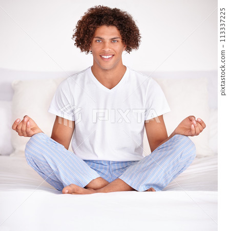 Man, portrait and meditation or relaxing in bed, lotus position and calming yoga at home. Male person, spiritual awareness and mindfulness in bedroom, morning routine and peaceful aura for wellness 113337225
