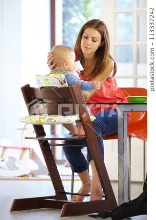 Woman, baby and food in feeding chair for nutrition, growth and development at table in kitchen of home. Mother, infant and cleaning face after eating, napkin and routine for love, care and nurture 113337242