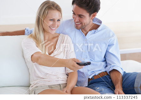 Happy couple, relax and watching TV on sofa for entertainment, holiday or weekend together at home. Man and woman smile with remote for streaming movie, series or shows in comfort on couch at house 113337245