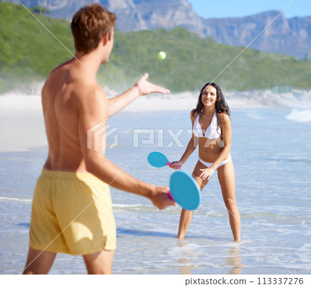 Travel, paddle ball and couple on beach together, having fun or playing game on holiday in summer. Love, smile or happy with young man and woman in water by sea or ocean for bonding in nature Travel, paddle ball and couple on beach together, having fun or playing game on holiday in summer. Love, smile or happy with young man and woman in water by sea or ocean for bonding in nature 113337276
