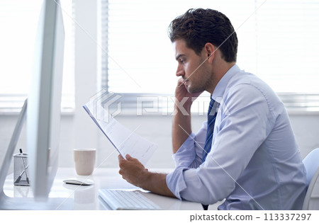Businessman, paper and computer in office for report, information and brainstorming with notes at desk. Professional man, document with reading and planning for budget, schedule or agenda at work 113337297