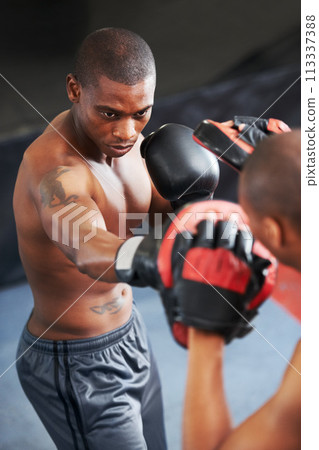 Boxing, coaching and black man with personal trainer in gym for power, fitness or training challenge. Strong body, sparring partner and boxer in ring with fist up, workout and confidence in fight. 113337388