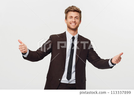 Portrait, thumbs up and celebration with a business man in studio isolated on a white background for success. Smile, target or goals and a confident young employee in a suit for an emoji hand gesture 113337899