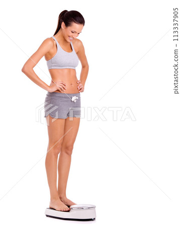 Finally. Scale, happy and woman in studio for weight loss, health and wellness diet victory or success. Smile, fitness and person measuring body for exercise, workout or training by white background. Finally. Scale, happy and woman in studio for weight loss, health and wellness diet victory or success. Smile, fitness and person measuring body for exercise, workout or training by white background. 113337905