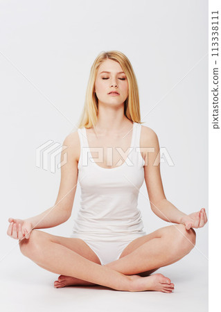 Calm, meditation and woman in lotus pose in a studio for spiritual, body and mind wellness. Balance, health and young female person in underwear for zen and relaxing routine by white background. Calm, meditation and woman in lotus pose in a studio for spiritual, body and mind wellness. Balance, health and young female person in underwear for zen and relaxing routine by white background. 113338111