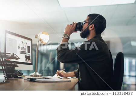 A bit of coffee keeps him in the game. a young businessman having coffee and using a computer during a late night in a modern office. A bit of coffee keeps him in the game. a young businessman having coffee and using a computer during a late night in a modern office. 113338427