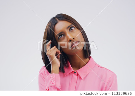 I trying to remember...Studio shot of a young woman looking thoughtful against a gray background. 113339686
