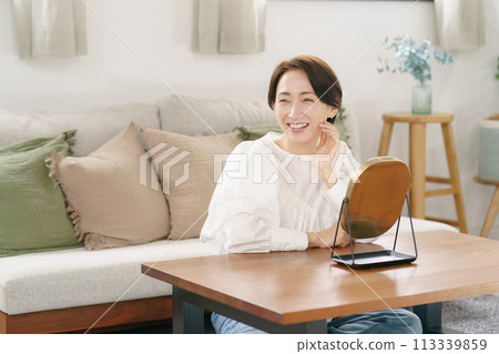 Woman smiling in the mirror in the living room Woman smiling in the mirror in the living room 113339859