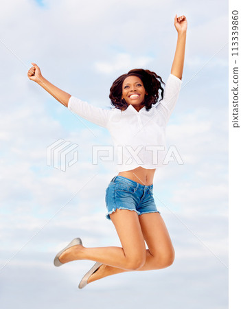 Black woman, jumping and excited in air with travel, vacation of winner happy from holiday. Winning, African person and leap with joy from celebration, achievement and freedom outdoor with smile Black woman, jumping and excited in air with travel, vacation of winner happy from holiday. Winning, African person and leap with joy from celebration, achievement and freedom outdoor with smile 113339860