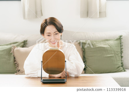 一個女人在客廳看著鏡子微笑 一個女人在客廳看著鏡子微笑 113339916