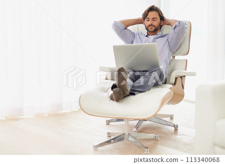 Businessman, relax and sofa with computer online for remote work, living room and home office for freelance job. Male person, social media and browsing or research on laptop, couch and smile Businessman, relax and sofa with computer online for remote work, living room and home office for freelance job. Male person, social media and browsing or research on laptop, couch and smile 113340068