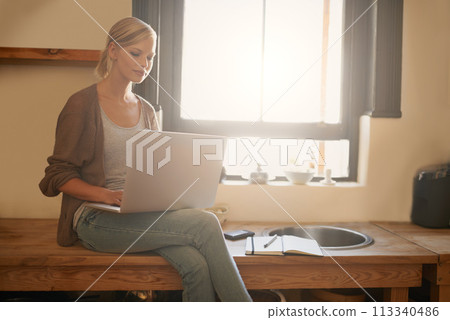 Woman, freelancer and laptop for journalism, remote work and internet connection in kitchen for info. Female person, editor and website for research or online news, blog and typing an article on tech 113340486