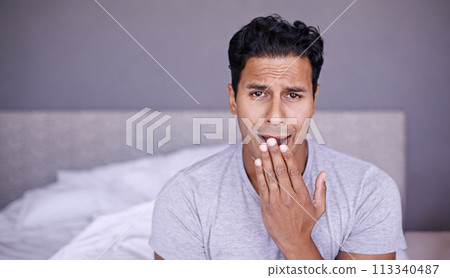 Man, yawn and tired in bedroom in portrait, fatigue and insomnia with sleep problem in morning. Young person, sleepy face or exhausted on break on lazy weekend, pyjamas or stress on bed in apartment 113340487