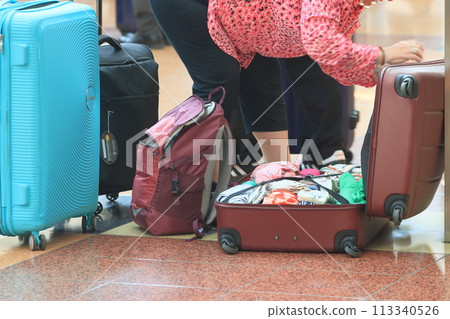 Airplane passengers sorting suitcases; packing at the airport 113340526