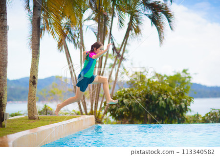Kids jump into swimming pool. Summer water fun. 113340582