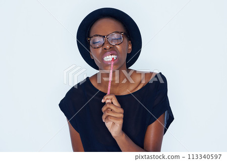 Face, fashion and black woman eating candy in studio on white background for sugar craving. Food, glasses and biting sweets with young african model eyes closed for appetite, greed or hunger 113340597
