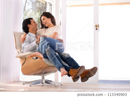 Laughing, conversation and couple on chair in living room at home with comfortable romance and care. Happy, marriage and young man and woman sitting, talking and bonding together in lounge at house. Laughing, conversation and couple on chair in living room at home with comfortable romance and care. Happy, marriage and young man and woman sitting, talking and bonding together in lounge at house. 113340903