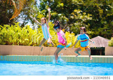 Kids jump into swimming pool. Summer water fun. Kids jump into swimming pool. Summer water fun. 113340931
