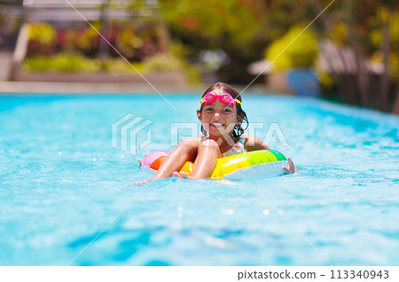 Child in swimming pool on toy ring. Kids swim. 113340943