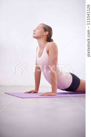 Fitness, pilates and wellness with woman in cobra pose on floor of studio for awareness or mindfulness. Exercise, yoga or zen and confident young person on mat with eyes closed for balance or peace Fitness, pilates and wellness with woman in cobra pose on floor of studio for awareness or mindfulness. Exercise, yoga or zen and confident young person on mat with eyes closed for balance or peace 113341126