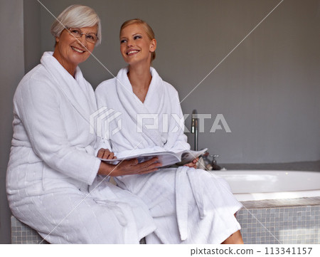 Mother, lady and smile with magazine and robe in bathroom for beauty, skincare and cosmetic treatment. Senior person and daughter on tub in spa with gown and article for wellness, hygiene and care Mother, lady and smile with magazine and robe in bathroom for beauty, skincare and cosmetic treatment. Senior person and daughter on tub in spa with gown and article for wellness, hygiene and care 113341157