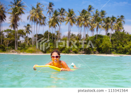 Young woman with surf board on tropical beach 113341564