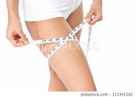 Woman, legs and tape measure for weight loss, slim body or health and wellness on a white studio background. Closeup of female person or model measuring thigh in diet, fitness or healthcare on mockup Woman, legs and tape measure for weight loss, slim body or health and wellness on a white studio background. Closeup of female person or model measuring thigh in diet, fitness or healthcare on mockup 113341582