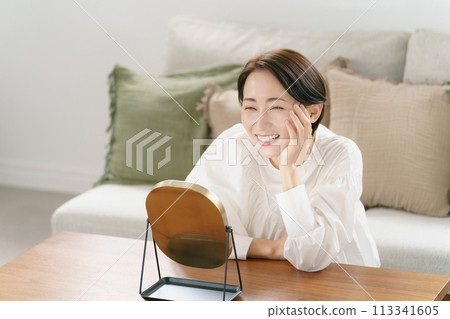 一個女人在客廳看著鏡子微笑 113341605