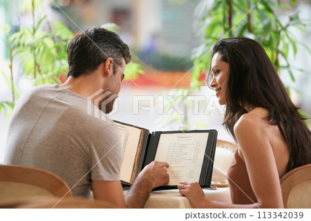 Couple, restaurant and reading a menu for selection, decision and bonding on valentines day. People, back and romance at cafe or lunch choice for anniversary celebration, cuisine and happy at bistro 113342039