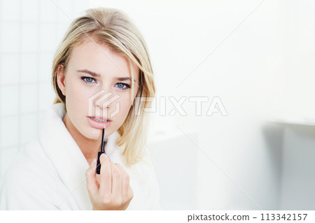 Woman, portrait and blond with lipstick for makeup, beauty or cosmetics in bathroom or facial treatment at home. Face of attractive young female person applying lip gloss, product or glow at house Woman, portrait and blond with lipstick for makeup, beauty or cosmetics in bathroom or facial treatment at home. Face of attractive young female person applying lip gloss, product or glow at house 113342157