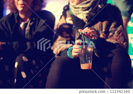 Hands, drink and friends outdoor at a music festival together for an event, show or performance. Cup, cocktail and alcohol with a person at a night carnival for celebration or entertainment closeup Hands, drink and friends outdoor at a music festival together for an event, show or performance. Cup, cocktail and alcohol with a person at a night carnival for celebration or entertainment closeup 113342160