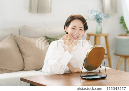 Woman smiling in the mirror in the living room Woman smiling in the mirror in the living room 113342257