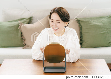 Woman smiling in the mirror in the living room Woman smiling in the mirror in the living room 113342300