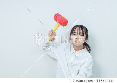 一個女孩帶著憤怒的表情揮舞著錘子 113342538