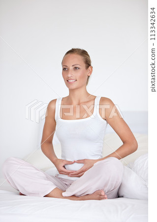 Happy woman, zen and relax on bed for morning, health or wakeup in calm comfort at home. Young female person holding stomach or tummy in zen, meditation or awareness sitting in bedroom at house Happy woman, zen and relax on bed for morning, health or wakeup in calm comfort at home. Young female person holding stomach or tummy in zen, meditation or awareness sitting in bedroom at house 113342634