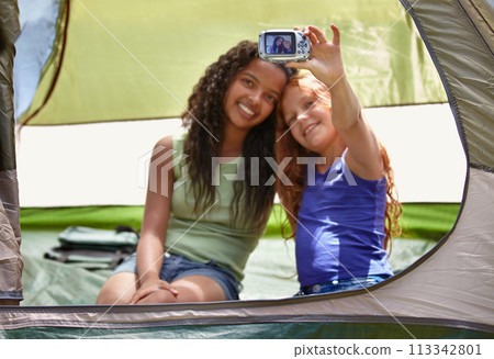 Happy girl, friends and selfie in tent for memory, camping or photography together with camera. Young female person, child or kids with smile for picture, photo or social media in relax or friendship 113342801