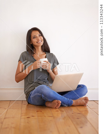 Wall background, laptop and woman with coffee on floor of apartment, home and smile with mug. Happiness, female person and girl watching movies on site of app online with technology and internet 113343244
