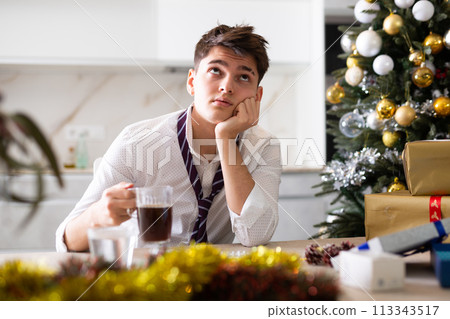 Young lonely man drinking alcohol at christmas table at home 113343517
