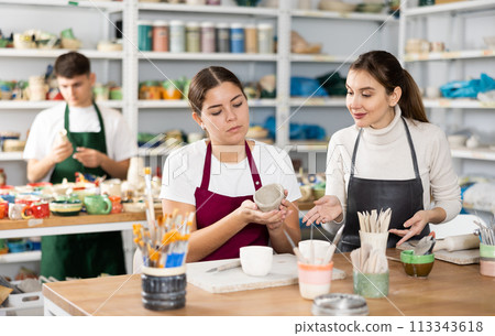 Joyous young women sculpting handmade cups Joyous young women sculpting handmade cups 113343618