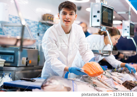 Portrait of man offering female customer fresh fish at seafood shop 113343811