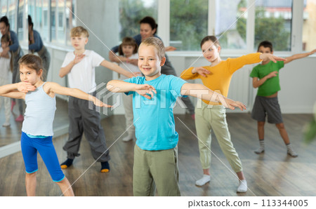 Group of preteen girls and boys enjoying active dance movement in studio Group of preteen girls and boys enjoying active dance movement in studio 113344005