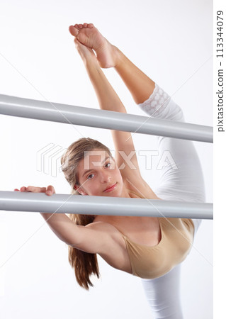 Portrait, ballet and girl stretching legs on barre in classroom, practice and student exercise. Ballerina, flexibility and warm up for training, dance choreography for art or performance for fitness 113344079