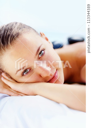 Portrait, spa and woman with hot stone massage, relax or stress relief body treatment at a wellness resort. Luxury, zen and face of female person at a salon for healing, therapy or vacation pamper 113344389