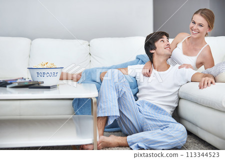 Couple, film and lying with living room, popcorn and sofa for relaxation and love or smile. People, home and romance for comfortable valentines day date and happiness for video or streaming movie 113344523