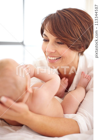 Mother, baby and happiness or love, play and relaxing on bed, bonding and joy in parenthood. Mom, newborn and peace or calm at home, positive and happy for child development, smile and fun together 113344587