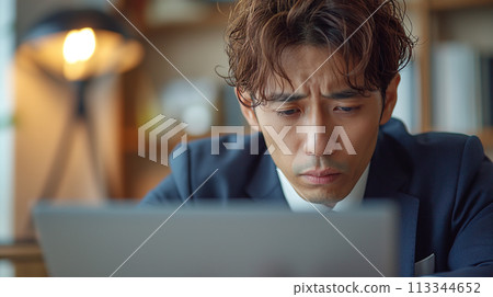A businessman holding a head in front of a personal computer A businessman holding a head in front of a personal computer 113344652