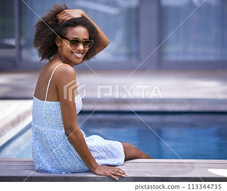 African woman, outside and pool for vacation in summer, sitting and happy for trip with sunglasses. Holiday for relax and casual for swimming and happiness for wellness with natural female model African woman, outside and pool for vacation in summer, sitting and happy for trip with sunglasses. Holiday for relax and casual for swimming and happiness for wellness with natural female model 113344735