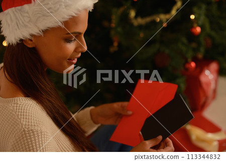 Happy woman, christmas tree and letter with card for message, wishes and care on holiday season in home. Person, smile or note by present for xmas greeting, gratitude or kindness in spirit of giving 113344832