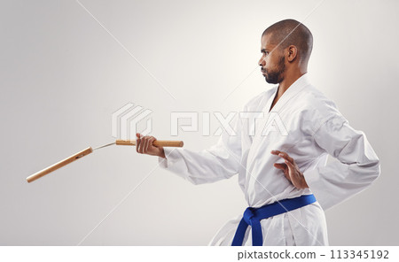Nunchucks, karate and man in martial arts fight with weapon in training for defence in white background of studio. Nunchaku, exercise and fighting with equipment in sport with skill and power in club 113345192