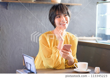 A woman operating a smartphone at a cafe "Western confectionery store sentiment" 113345223